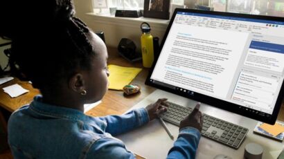 Young person using a wireless keyboard to work on a document in Microsoft Word on a large desktop monitor