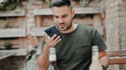 man in gray crew neck long sleeve shirt holding black smartphone