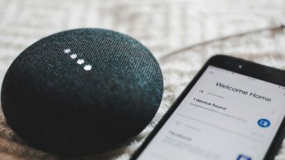 Turned-on charcoal Google Home Mini and smartphone photo