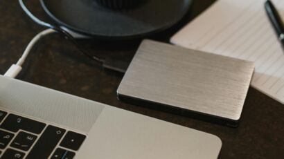 Free Closeup of an external hard drive connected to a laptop with a USB cable on a desk. Stock Photo