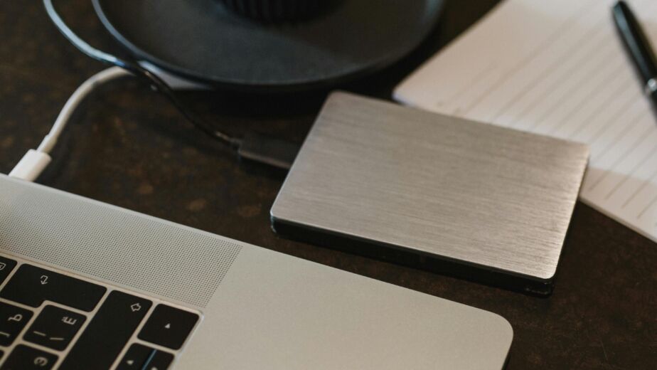 Free Closeup of an external hard drive connected to a laptop with a USB cable on a desk. Stock Photo