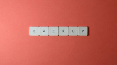 Free Close-up of keyboard keys spelling 'BACKUP' placed on a coral-colored surface. Stock Photo