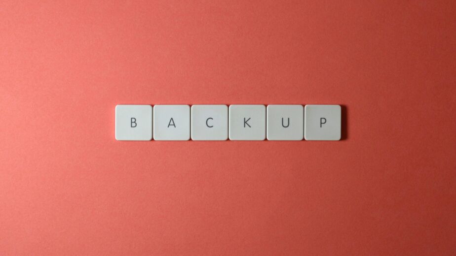 Free Close-up of keyboard keys spelling 'BACKUP' placed on a coral-colored surface. Stock Photo