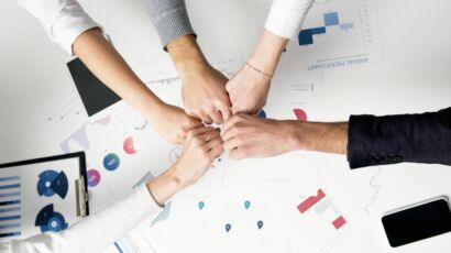 Free Colleagues celebrate success with a fist bump over financial charts depicting teamwork and unity. Stock Photo