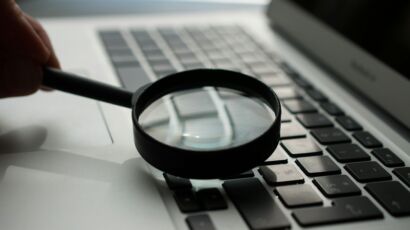magnifying glass near gray laptop computer